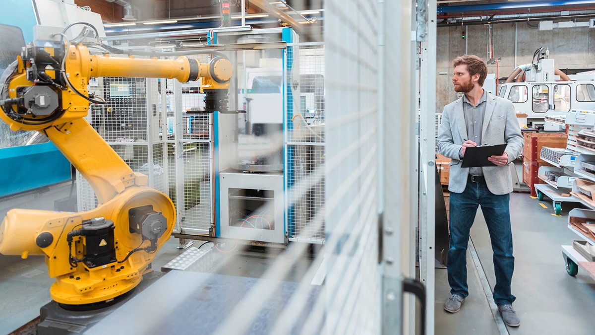 Engineer monitors an industrial robot in automated manufacturing